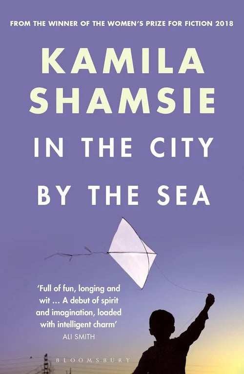 Book cover of 'In the City by the Sea' by Kamila Shamsie with a silhouette of a person flying a kite against a purple sky.