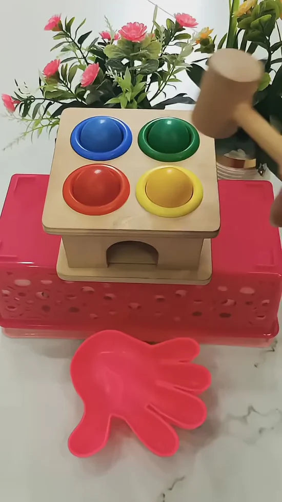 Colorful wooden toy with red base and flowers in the background