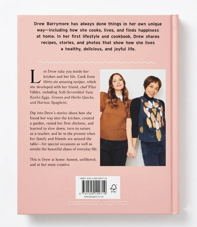 Back cover of a book titled 'Drew Barrymore: The Life and Recipes' on a solid pink background, featuring text about Drew's cooking and lifestyle, a photo of her with a man, and a barcode at the bottom.