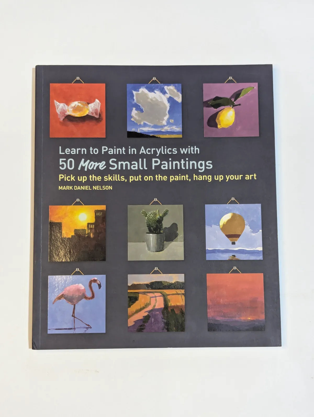 Book cover of 'Learn to Paint in Acrylics with 50 More Small Paintings' by Mark Daniel Nelson, featuring small paintings on a gray background.