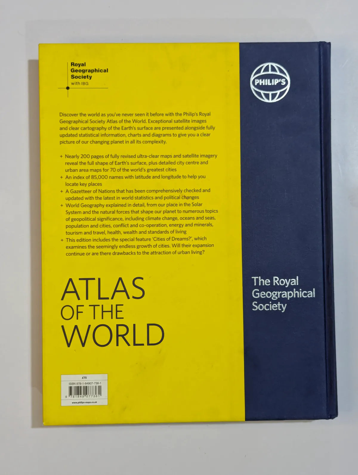 Back cover of an atlas with yellow and blue design, featuring the Royal Geographical Society logo.