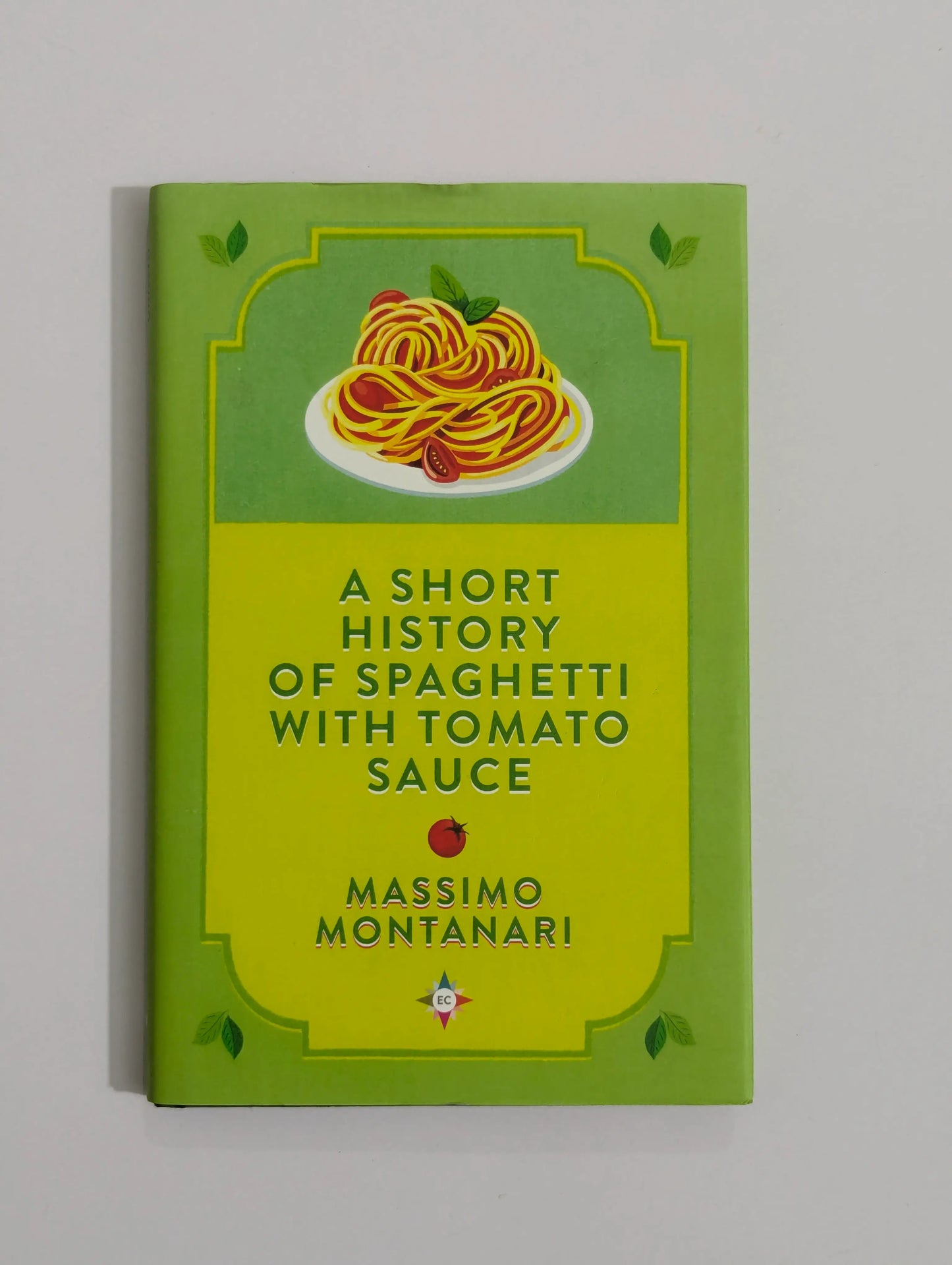 A book titled 'A Short History of Spaghetti with Tomato Sauce' by Massimo Montanari, featuring a bright lime green cover with an illustration of spaghetti on a plate at the top.