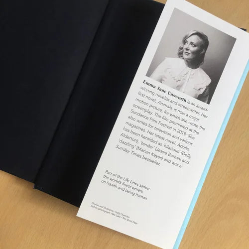Book open to a page with a portrait and text of a woman, placed on a wooden surface.