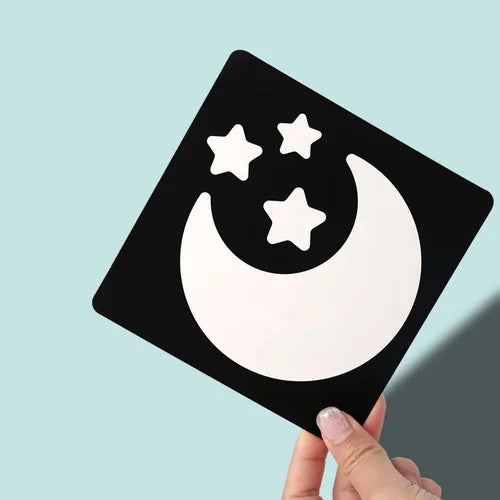 Black square sticker with a white moon and stars design held against a light blue background