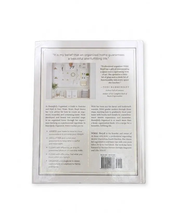 The back cover of a book, titled 'The Art of Organizing' by Nikki Boyd, shown against a plain white background. The cover features a white background with black text, a small color photograph of an organized home interior, and a barcode at the bottom right.