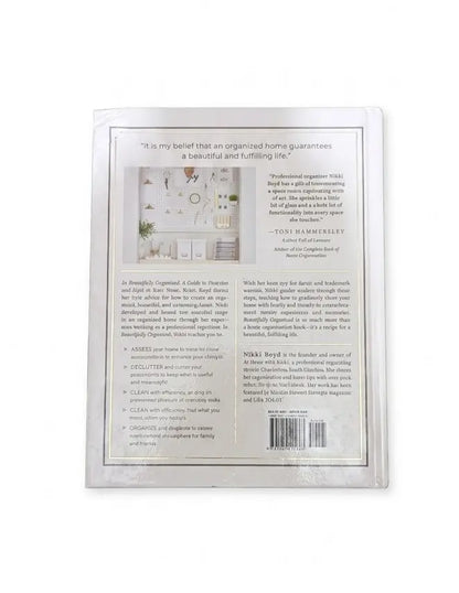 The back cover of a book, titled 'The Art of Organizing' by Nikki Boyd, shown against a plain white background. The cover features a white background with black text, a small color photograph of an organized home interior, and a barcode at the bottom right.