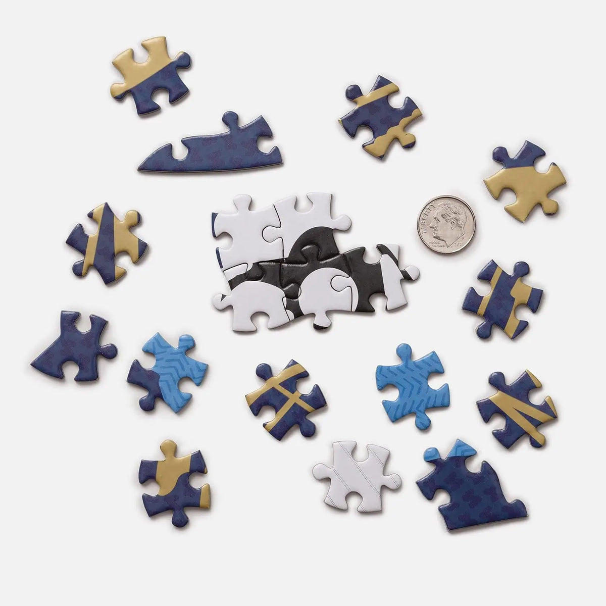 Assorted puzzle pieces in blue, white, and gold on a white background with a coin for scale.