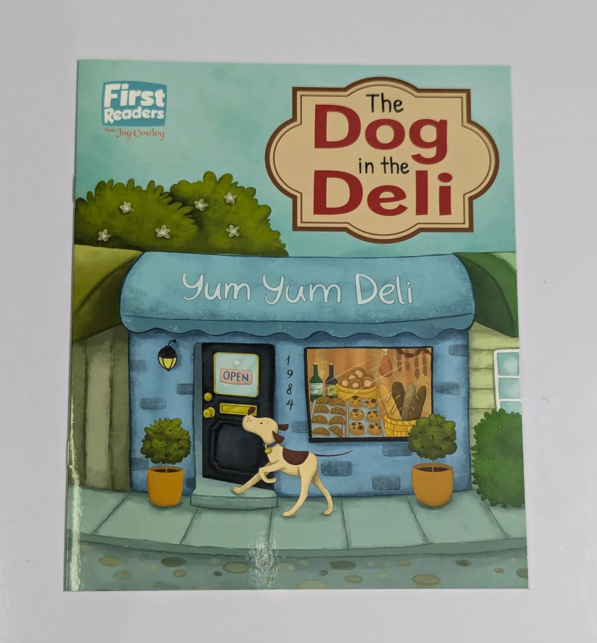Book cover of 'The Dog in the Deli' with a cartoon dog walking towards a deli.