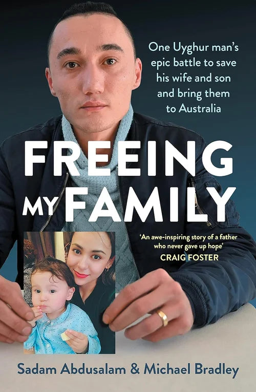Book cover of 'Freeing My Family' with a man holding a photo of his family against a dark background.