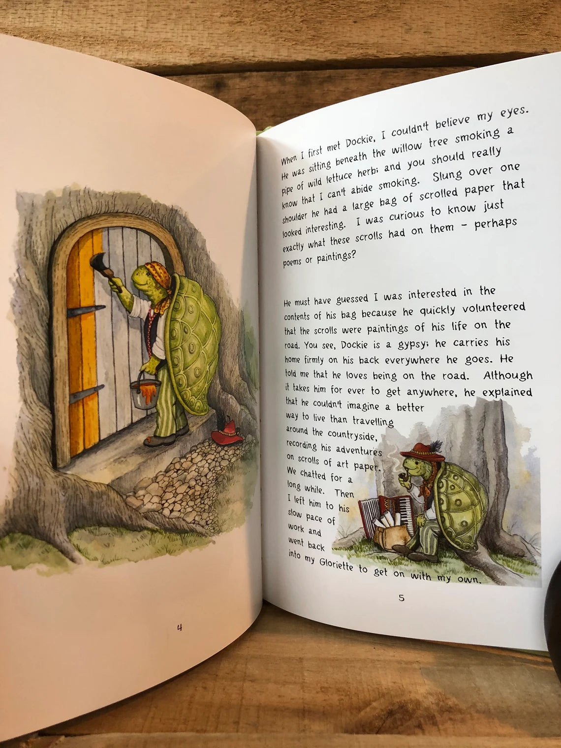 Open book with illustrated pages of a gypsy and a tree house on a wooden surface