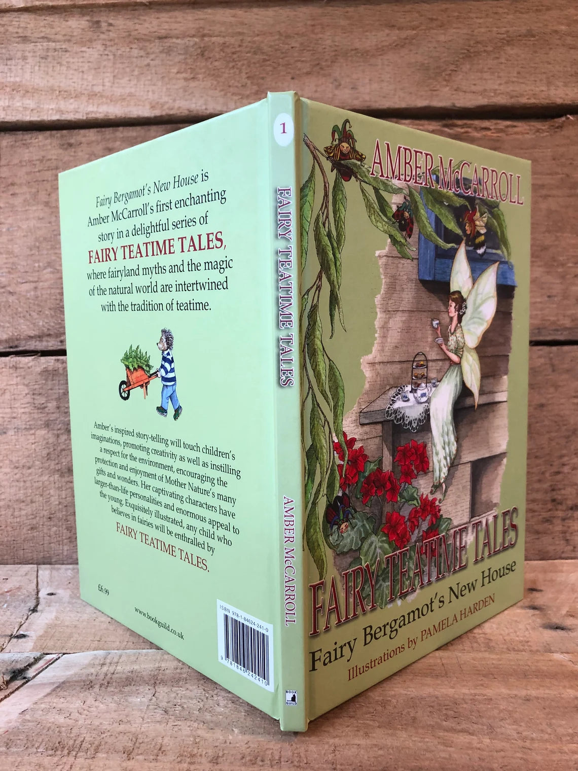 Book titled 'Fairy Teatime Tales' with a fairy and garden scene on a wooden background