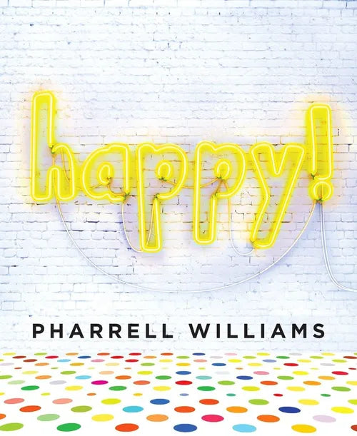 Neon sign spelling 'happy!' on a white brick wall with Pharrell Williams' name below.