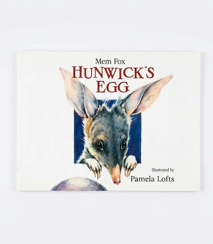 The front cover of the children's book 'Mem Fox: Hunwick's Egg' by Pamela Lofts, featuring an illustration of a small gray and pink marsupial peeking out of a blue square on an off-white background.