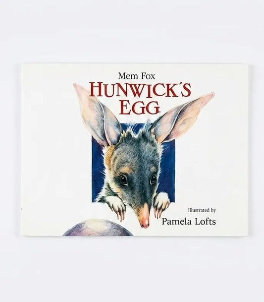 The front cover of the children's book 'Mem Fox: Hunwick's Egg' by Pamela Lofts, featuring an illustration of a small gray and pink marsupial peeking out of a blue square on an off-white background.