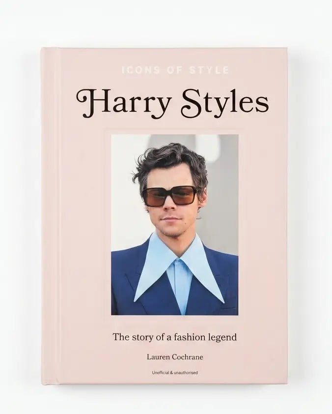 A hardcover book titled 'Icons of Style Harry Styles' by Lauren Cochrane, featuring a pale pink cover with a central portrait of Harry Styles in sunglasses, a blue suit, and a light blue shirt.