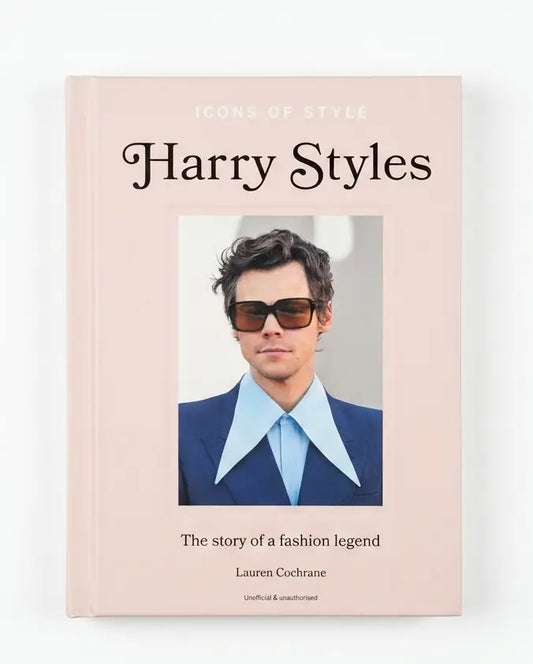 A hardcover book titled 'Icons of Style Harry Styles' by Lauren Cochrane, featuring a pale pink cover with a central portrait of Harry Styles in sunglasses, a blue suit, and a light blue shirt.
