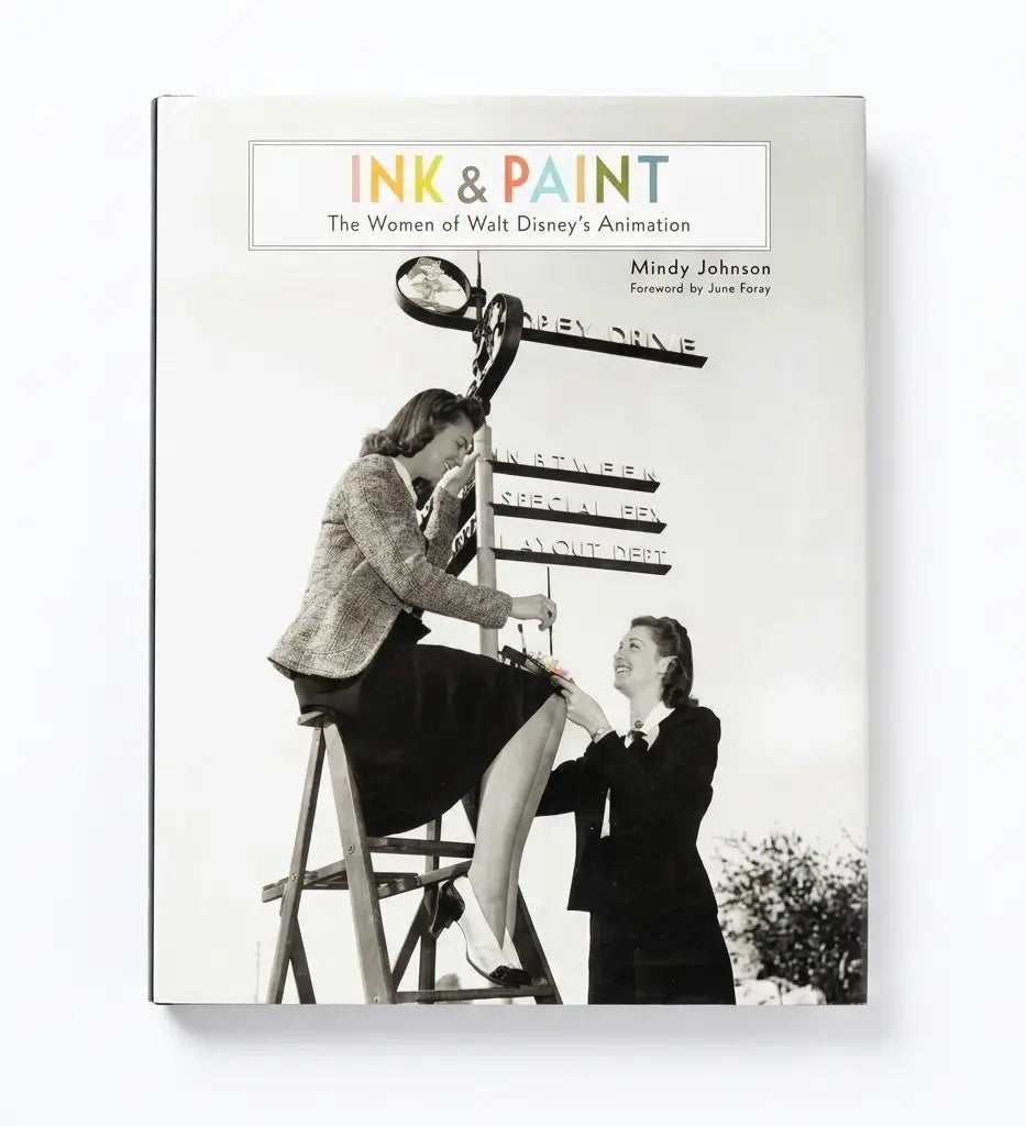 A hardcover book titled 'Ink & Paint: The Women of Walt Disney's Animation' by Mindy Johnson, featuring a black-and-white cover photo of two women working on a signpost, shown against a plain white background.