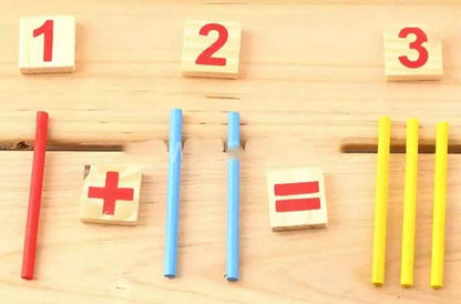 Educational math setup with number blocks and sticks on a wooden surface