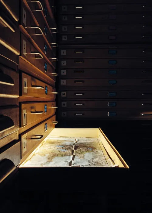 Wooden archive drawers with an open drawer revealing a map.