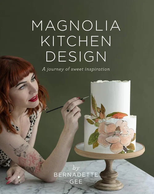 Book cover of 'Magnolia Kitchen Design' with a woman painting a cake on a green background