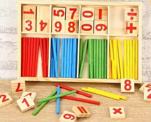 Colorful mathematical teaching aids including wooden blocks with numbers and colored sticks on a wooden surface.