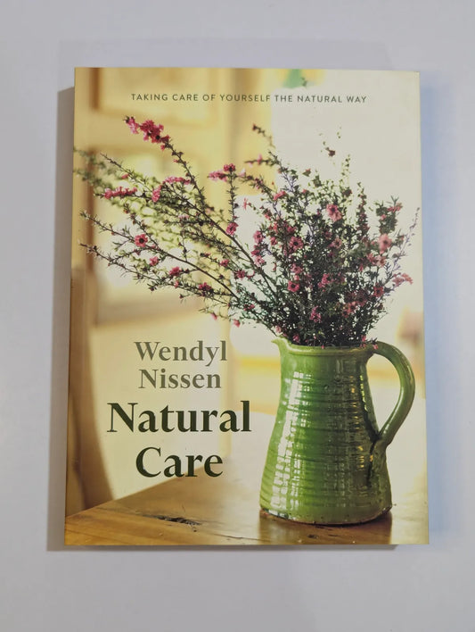 Book cover of 'Natural Care' by Wendyl Nissen with a green pitcher and flowers on a wooden surface.