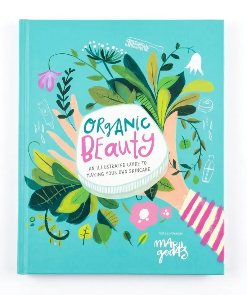 The front cover of the hardcover book 'Organic Beauty' by The Beauty Merchants, featuring a vibrant turquoise background decorated with green leaves, pink flowers, and illustrated hands holding a jar of skincare.