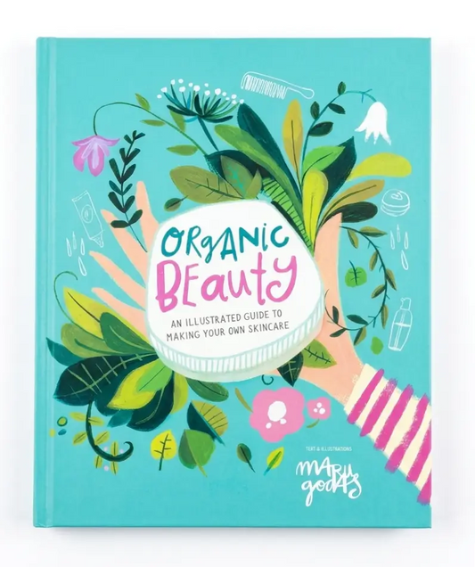 The front cover of the hardcover book 'Organic Beauty' by The Beauty Merchants, featuring a vibrant turquoise background decorated with green leaves, pink flowers, and illustrated hands holding a jar of skincare.