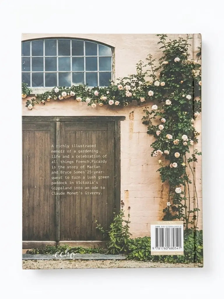 A hardcover book standing upright against a white background, showing the back cover with a photograph of a rustic beige wall, dark wooden door, window, and climbing white flowers. The title and subtitle text are printed on the cover, along with a barcode and small logo near the bottom.