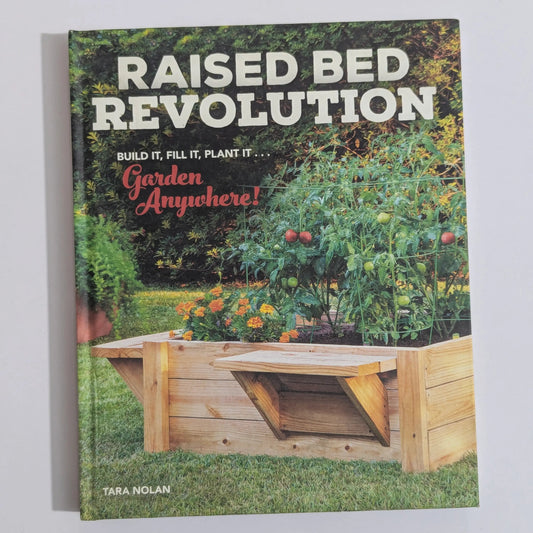 The front cover of the book 'Raised Bed Revolution' by Tara Nolan, featuring a wooden raised bed garden planter in a lush green garden setting. The title is displayed in large white letters at the top, with the subtitle 'Build It, Fill It, Plant It.
