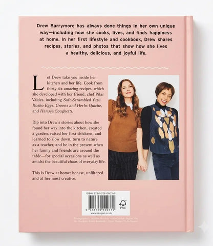 Back cover of a book titled 'Drew Barrymore: The Life and Recipes' on a solid pink background, featuring text about Drew's cooking and lifestyle, a photo of her with a man, and a barcode at the bottom.