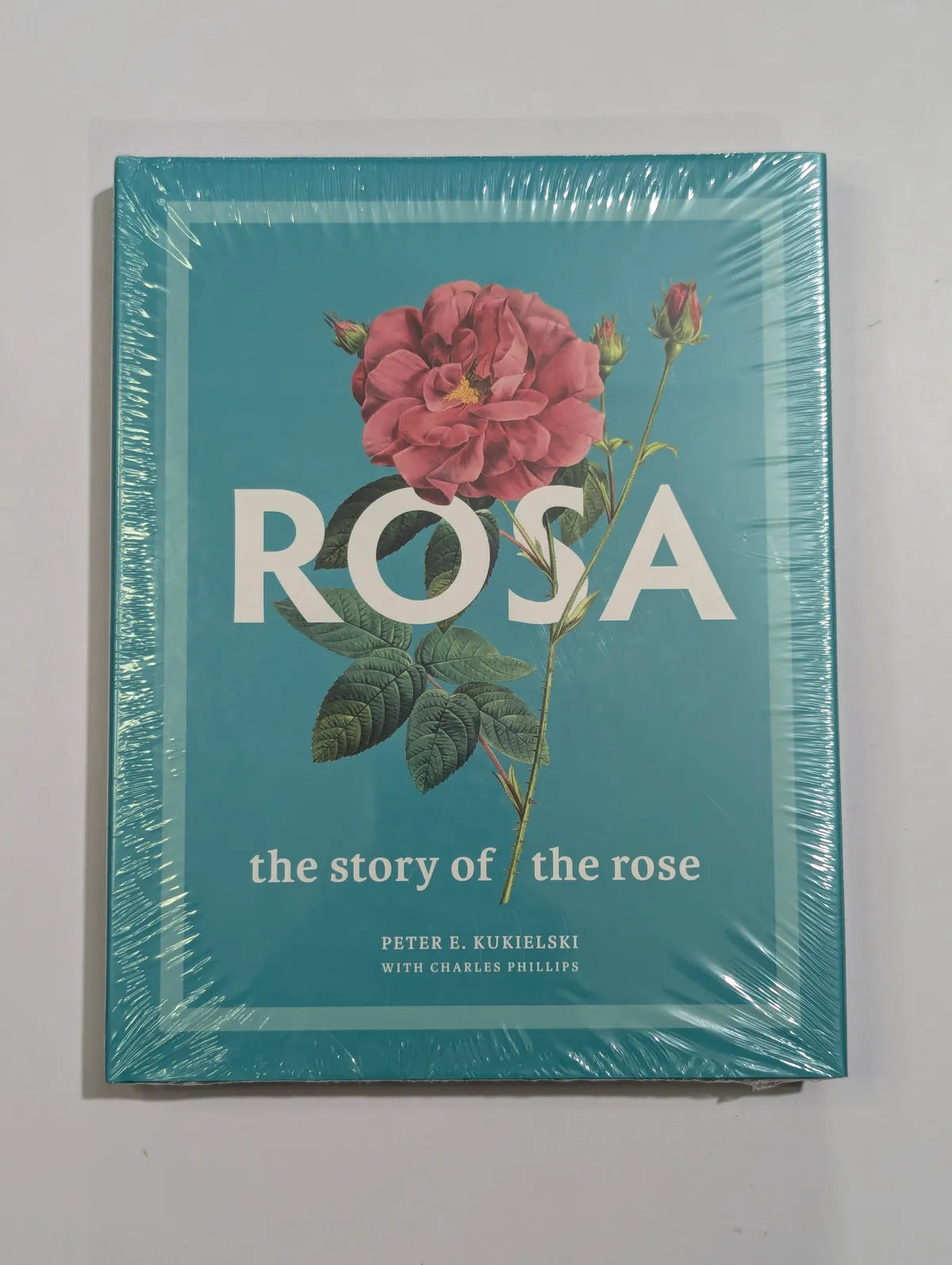 Book titled 'ROSA: the story of the rose' with a pink rose illustration on a teal background.