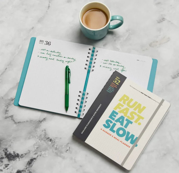 Open planner with a cup of coffee and a pen on a marble surface