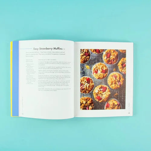 Open book showing a recipe for strawberry muffins on a teal background