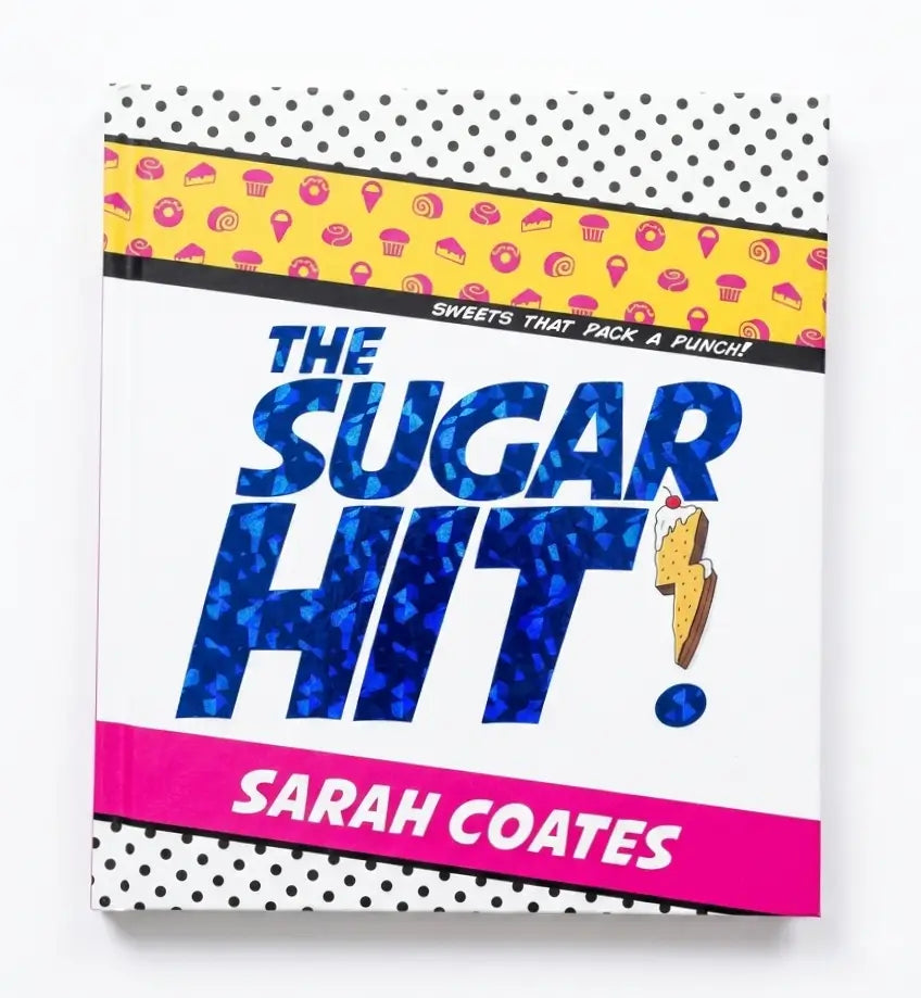 The Sugar Hit cookbook by Sarah Coates, featuring a retro pop-art style cover with bold blue glitter-textured lettering, a pink banner, and a yellow patterned band with dessert illustrations.